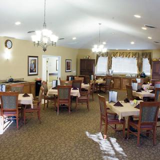 A cozy dining area with neatly arranged tables and chairs, featuring elegant lighting and decor.