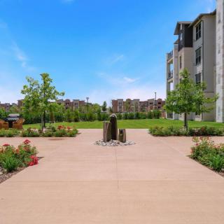 A modern building surrounded by a well-maintained garden and pathway under a clear blue sky.