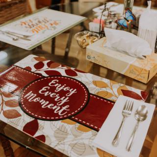 A beautifully set dining table with a colorful placemat and neatly arranged cutlery.