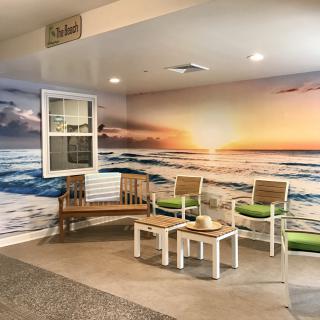A cozy indoor seating area featuring a vibrant beach sunset mural.