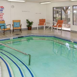 An indoor pool area with surrounding seating and tiled flooring.