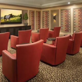 A modern home theater room with red chairs and a large screen on the wall.