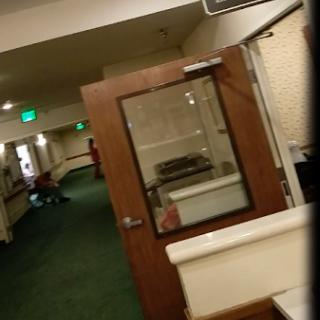 A view of a hallway featuring a door and green carpeting.