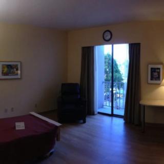 A hotel room featuring a bed, a window with curtains, and a view of the balcony.