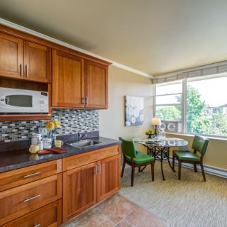 A cozy kitchen and dining area with wooden cabinets, a small round table, and a window providing natural light.