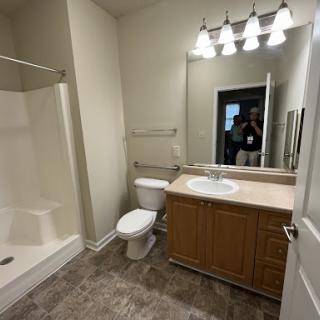 A modern bathroom featuring a sink, toilet, and shower area with stylish lighting.
