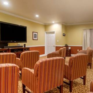 A cozy home theater room with several striped chairs facing a large television screen.