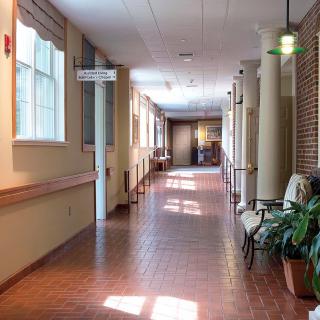 A well-lit interior hallway with brick flooring and seating areas along the side.