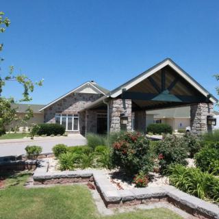 A well-maintained residential house with landscaped garden and clear blue skies.