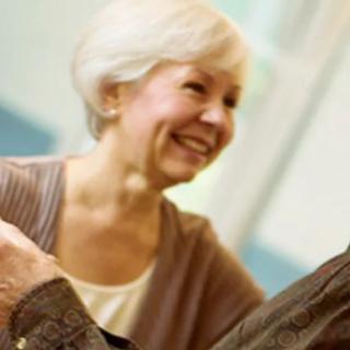 An elderly woman smiling and interacting with someone indoors.