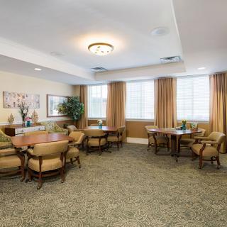 A well-furnished dining area with multiple tables and chairs, decorated with plants and artworks on the walls.