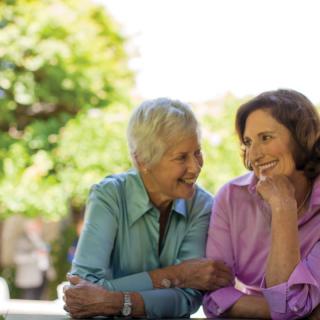 Two elderly women enjoying a conversation outdoors.