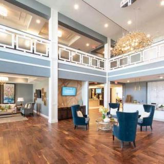 A luxurious and spacious living room with wooden flooring, modern furniture, and a large chandelier.
