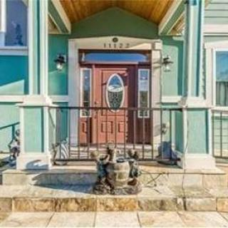A house entrance with a wooden door, statues, and stone steps.