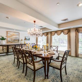 An elegant dining room featuring a wooden table, upholstered chairs, and a stunning chandelier.