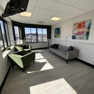 A bright and modern office waiting room featuring comfortable seating and colorful artwork.