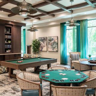 A stylish game room featuring a poker table and a billiards table, with modern decor and ambient lighting.
