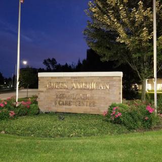 A night view of a welcoming sign at an institution, surrounded by landscaped greenery.