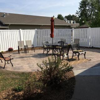 A neatly arranged patio area with outdoor furniture and an umbrella, enclosed by a white fence.