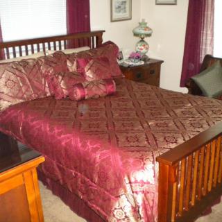 A cozy bedroom with a wooden bed frame and rich burgundy bedding.