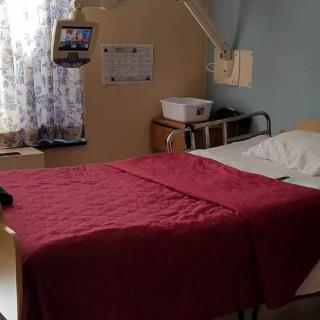 A hospital room with a neatly made bed and medical equipment.