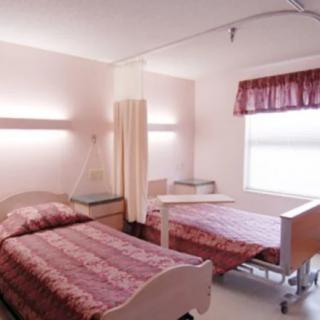 A hospital room with two beds and a curtain divider.