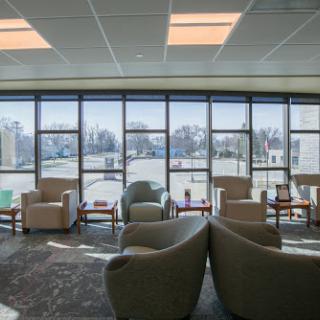 A spacious waiting room filled with comfortable chairs, illuminated by natural light streaming through large windows.