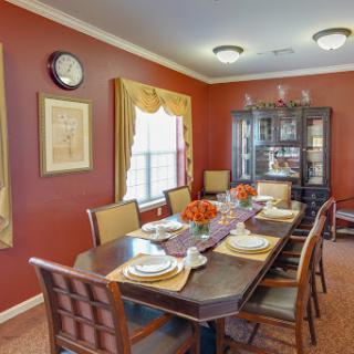 A beautifully arranged dining room featuring a wooden table set for a meal, adorned with elegant dinnerware against a warm brown wall.
