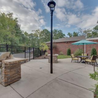 Outdoor patio area with furniture and a lamp post near a brick building.