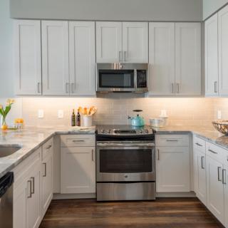 Modern kitchen with white cabinets and stainless steel appliances.