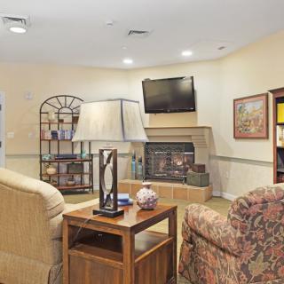 A cozy living room featuring a TV, bookshelf, and comfortable seating.