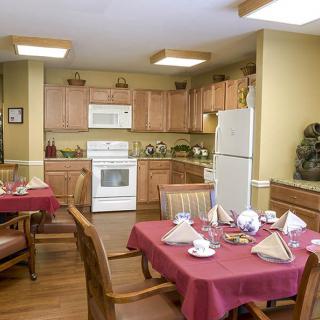 A cozy kitchen and dining area with neatly set tables, wooden cabinets, and modern appliances.