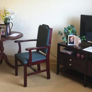 A cozy living room setup with a chair, table, and television, adorned with flowers and photographs.