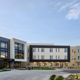 A modern, multi-story commercial building with a sleek design and large windows, surrounded by landscaped grounds.
