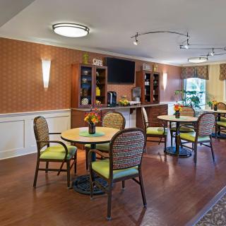 A cozy dining area with wooden flooring, tables, and comfortable seating.