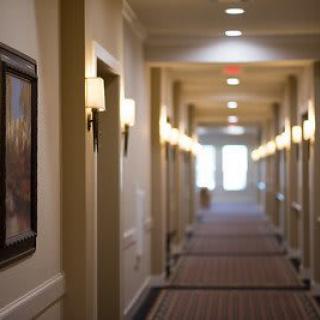A long, well-lit hallway with carpet and artwork on the walls.