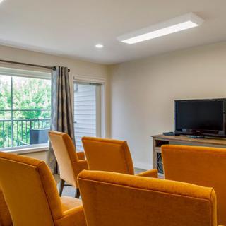 A cozy living room with bright orange chairs and a television near the window.