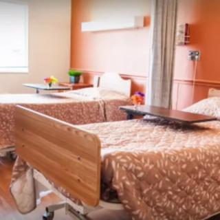 A hospital room with two patient beds and bedside tables.