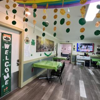 A festive dining area adorned with green decorations and a warm 'Welcome' sign.