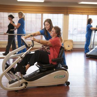 A physical therapist assists a patient using an exercise machine during a rehabilitation session.