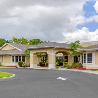 A single-story building with a large entrance and landscaped surroundings under a cloudy sky.