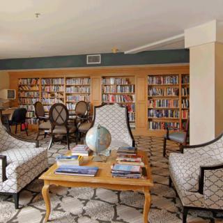 A cozy library with comfortable armchairs, filled bookshelves, and a globe on the coffee table.