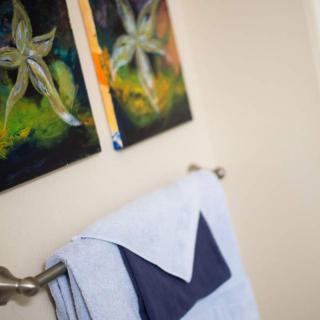 A neatly folded towel hangs beneath vibrant flower-themed artwork in a bathroom.