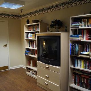 A cozy living room with bookshelves and a television.