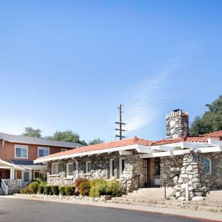A quaint stone-walled motel under a clear blue sky.