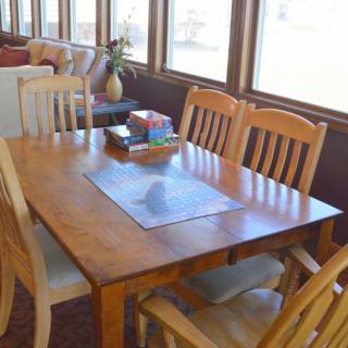 A sunlit dining area with a wooden table and chairs.