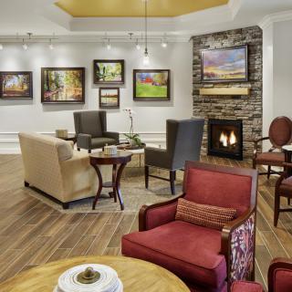 A cozy living room with comfortable seating, a fireplace, and art displayed on the walls.
