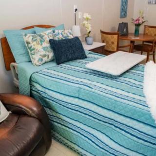 A neatly arranged bed in a hospital room, adorned with patterned pillows and a turquoise striped blanket.