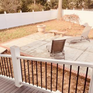 A backyard patio with seating, enclosed by a white fence.