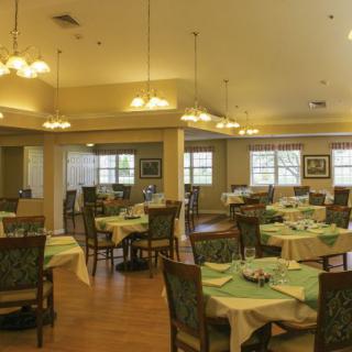 A spacious dining area with neatly arranged tables and chairs, featuring elegant lighting fixtures.